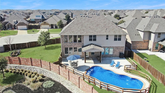 view of pool with a patio, a lawn, a fenced backyard, and a residential view