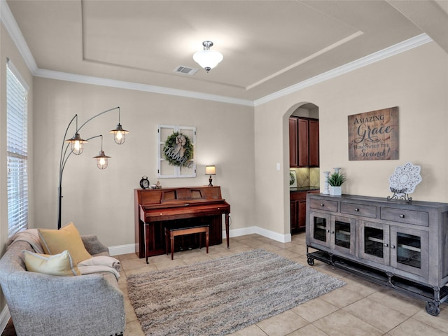 living area featuring arched walkways, light tile patterned flooring, visible vents, baseboards, and crown molding