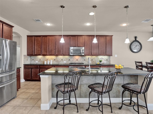 kitchen featuring appliances with stainless steel finishes, a sink, visible vents, and a kitchen breakfast bar