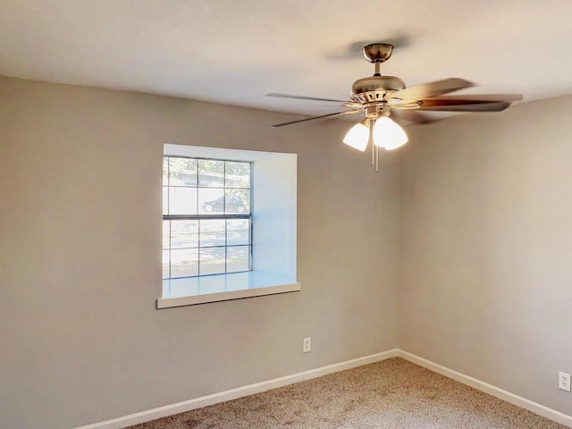 carpeted empty room featuring a ceiling fan and baseboards