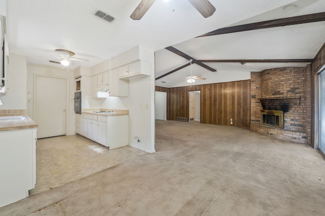 kitchen featuring wooden walls, light colored carpet, white cabinetry, open floor plan, and light countertops