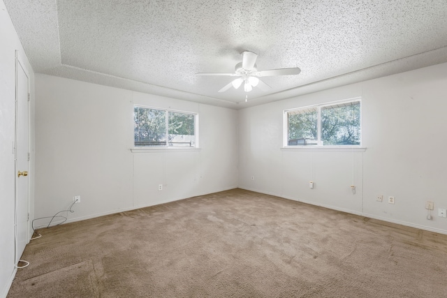 carpeted empty room with a healthy amount of sunlight, ceiling fan, and a textured ceiling