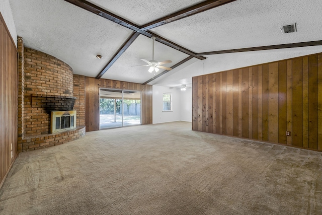 unfurnished living room featuring lofted ceiling with beams, carpet floors, a fireplace, and wooden walls