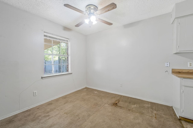 unfurnished dining area with light carpet, a ceiling fan, baseboards, and a textured ceiling