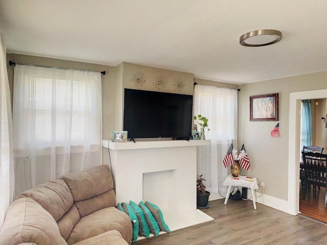 living room featuring a fireplace, baseboards, and wood finished floors