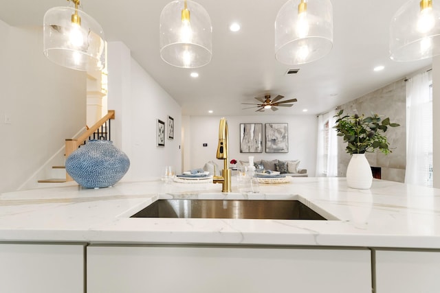 kitchen with visible vents, decorative light fixtures, light stone countertops, a sink, and recessed lighting