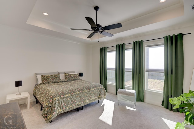 bedroom with baseboards, a tray ceiling, and light colored carpet