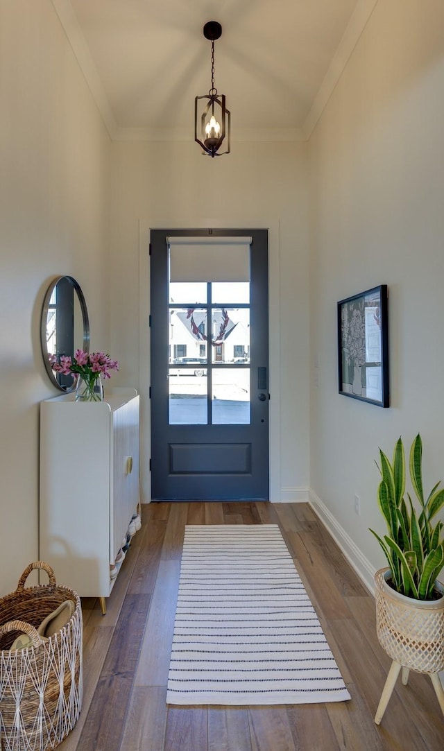 entryway with a notable chandelier, baseboards, wood finished floors, and crown molding