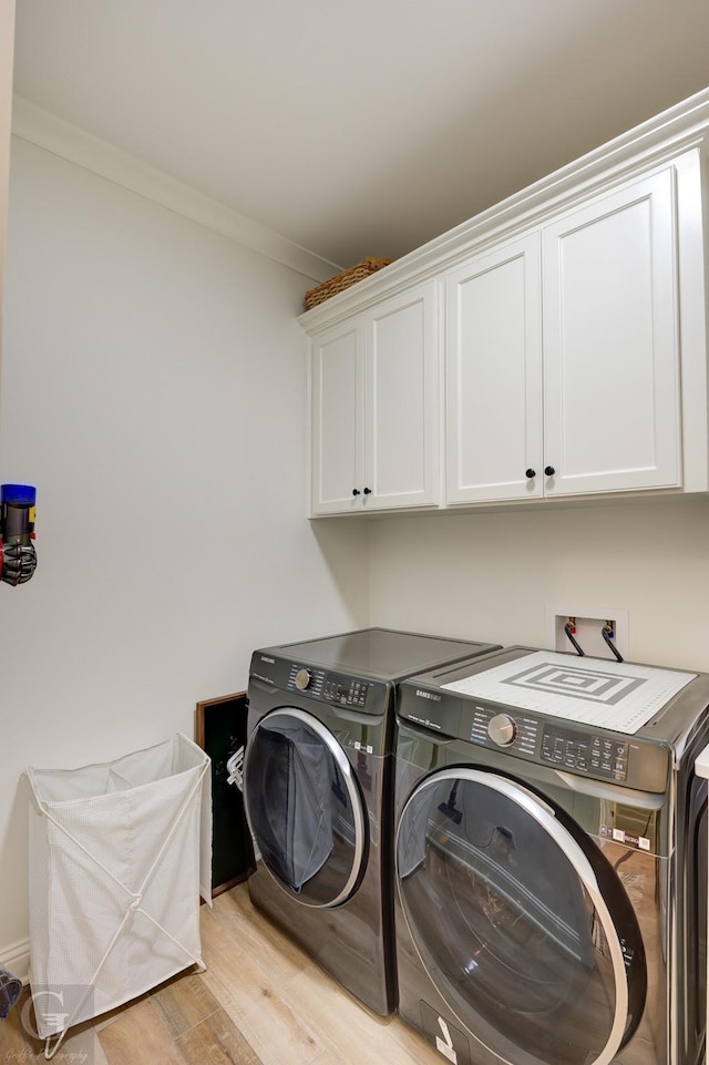 laundry area with ornamental molding, light wood finished floors, washing machine and dryer, and cabinet space