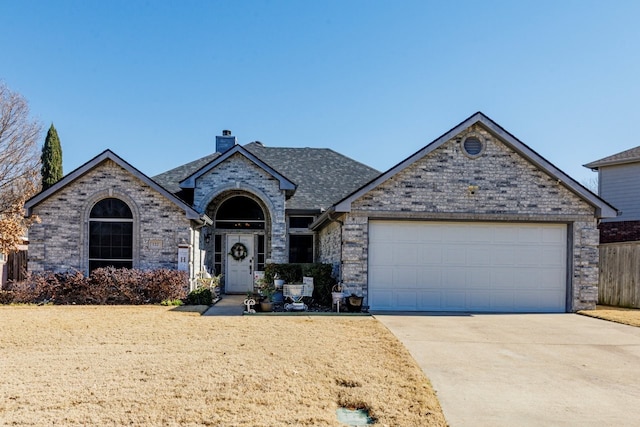 french country inspired facade with roof with shingles, brick siding, a chimney, concrete driveway, and an attached garage