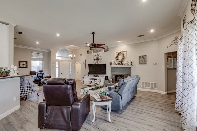 living area featuring light wood-style floors, a fireplace, visible vents, and ornamental molding