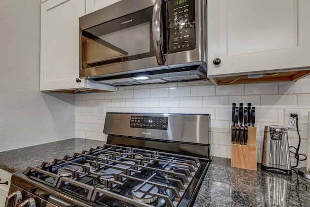 details featuring white cabinets, appliances with stainless steel finishes, decorative backsplash, and dark stone countertops