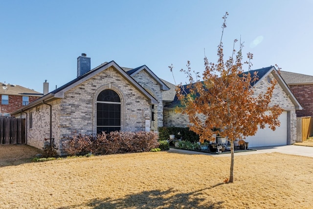 view of front of house featuring an attached garage, brick siding, fence, concrete driveway, and a chimney