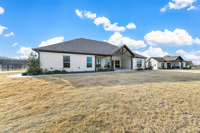 rear view of property featuring a yard and fence