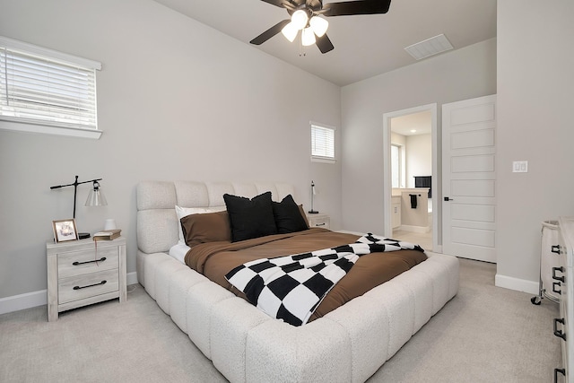 bedroom with light carpet, visible vents, baseboards, ensuite bath, and ceiling fan