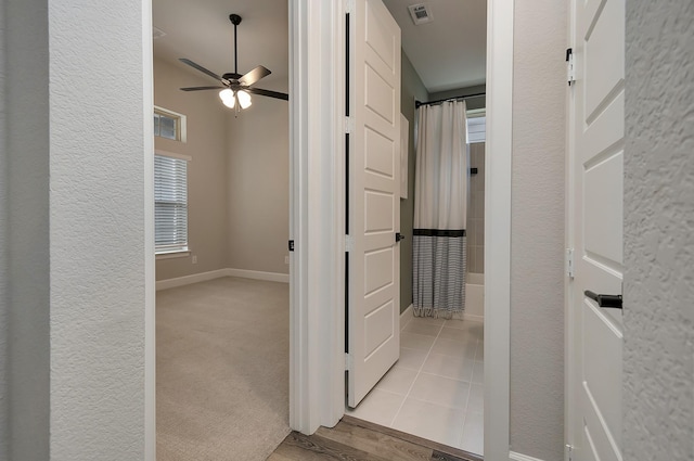 hall featuring light carpet, visible vents, and baseboards