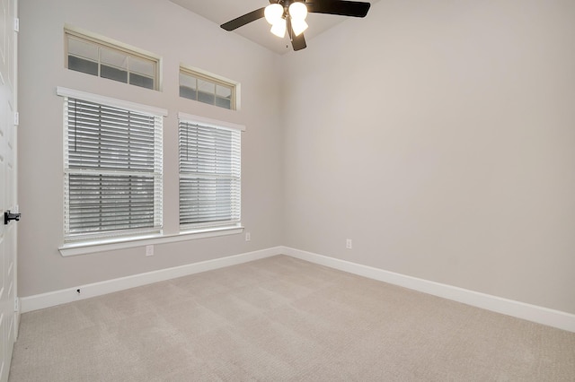 unfurnished room with baseboards, a ceiling fan, and light colored carpet