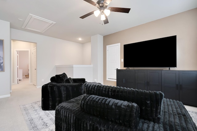 living area with attic access, light carpet, ceiling fan, and baseboards