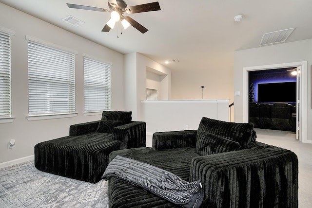 living room featuring a ceiling fan, visible vents, light carpet, and baseboards