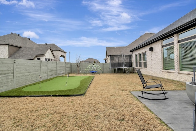 view of yard with a trampoline, a patio area, and a fenced backyard