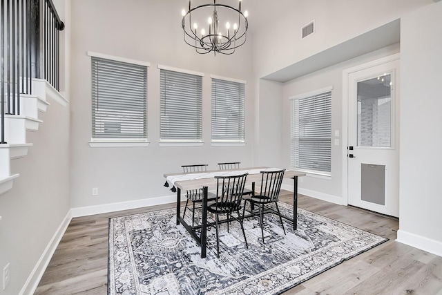 dining space featuring a chandelier, wood finished floors, visible vents, and baseboards