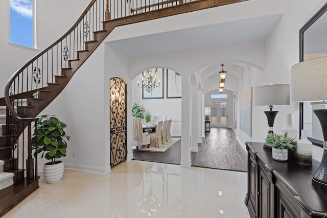 entrance foyer with arched walkways, baseboards, a high ceiling, and stairs