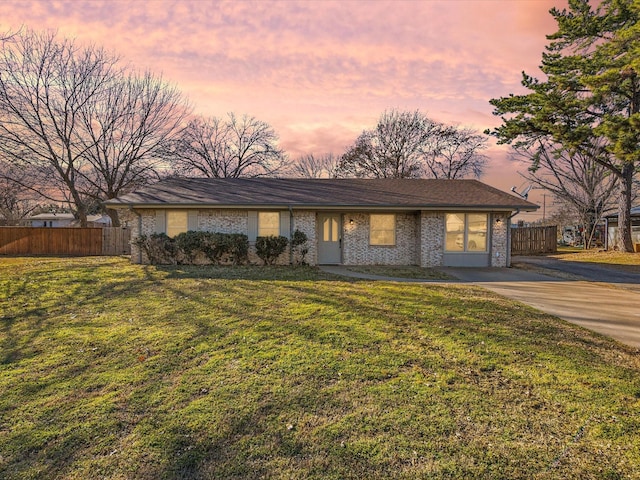 view of front of home featuring a yard, concrete driveway, and fence