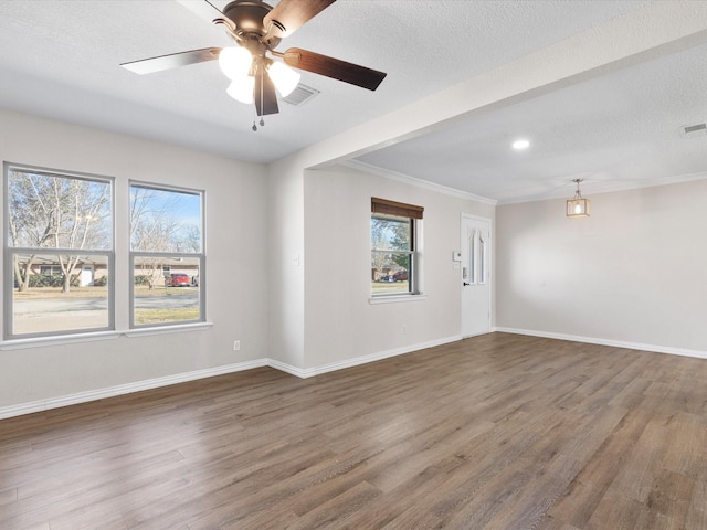 unfurnished room featuring a textured ceiling, wood finished floors, visible vents, and baseboards