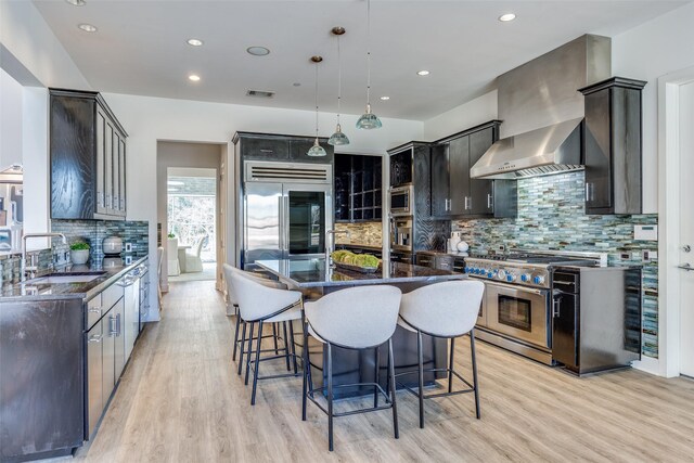 6007 Club Oaks Dr, Dallas, TX 75248 - kitchen featuring premium appliances, a sink, decorative backsplash, a kitchen breakfast bar, and light wood finished floors