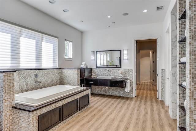 6007 Club Oaks Dr, Dallas, TX 75248 - bathroom with a garden tub, vanity, wood finished floors, recessed lighting, and tile walls