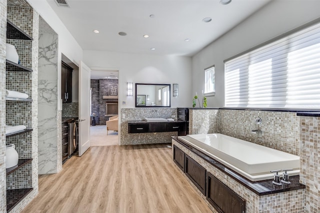 6007 Club Oaks Dr, Dallas, TX 75248 - bathroom with a garden tub, vanity, wood finished floors, tile walls, and recessed lighting