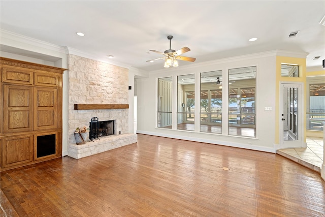 unfurnished living room featuring a fireplace, wood finished floors, visible vents, baseboards, and crown molding