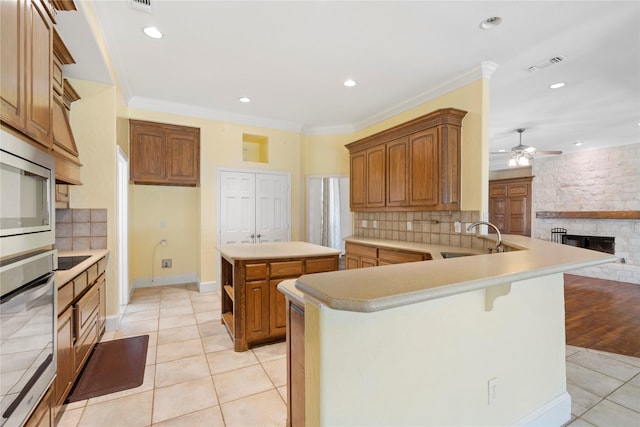 kitchen featuring a center island, a peninsula, stainless steel appliances, light countertops, and a sink