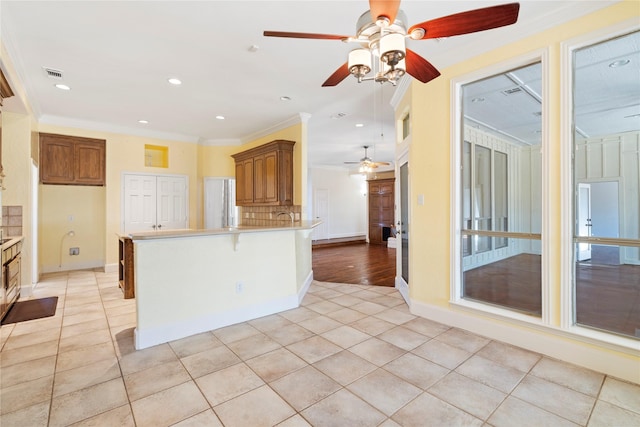 kitchen with ornamental molding, light countertops, brown cabinets, and a peninsula