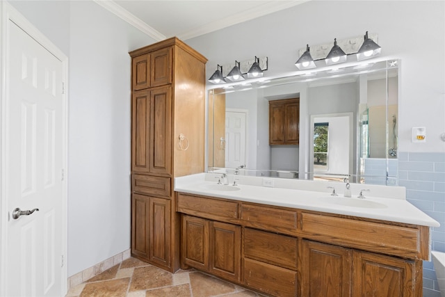 full bath with double vanity, a sink, stone tile flooring, and crown molding