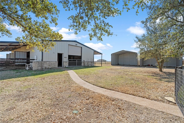 view of yard with a detached carport, fence, an outbuilding, and an outdoor structure