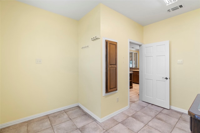 hall with light tile patterned floors, baseboards, and visible vents