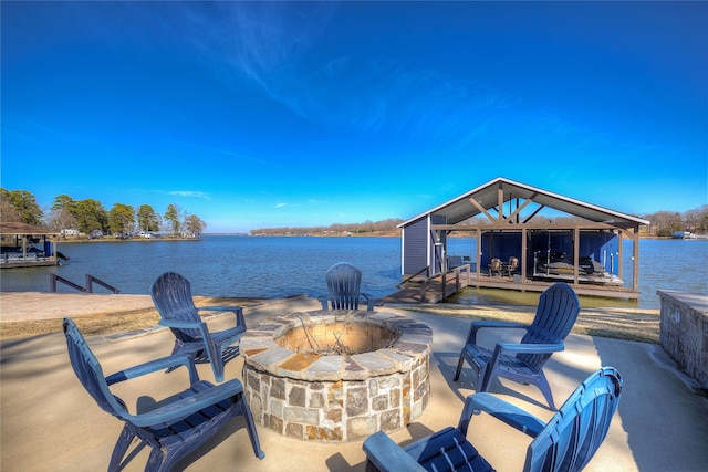 view of patio featuring a fire pit, a boat dock, and a water view