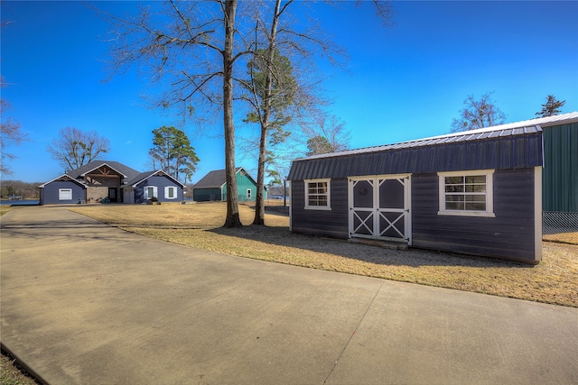 exterior space with a front lawn, an outbuilding, metal roof, and a gambrel roof