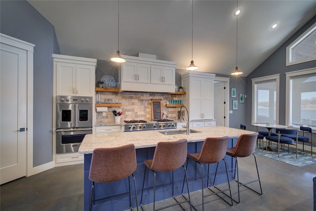 kitchen featuring white cabinetry, a center island with sink, a sink, and open shelves