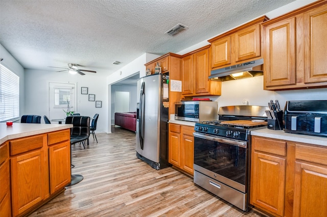 kitchen with stainless steel appliances, visible vents, light countertops, and under cabinet range hood