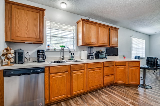 kitchen featuring a sink, plenty of natural light, light countertops, and dishwasher