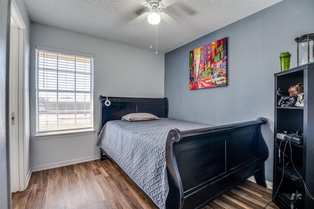 bedroom featuring a textured ceiling, ceiling fan, dark wood-style flooring, and baseboards