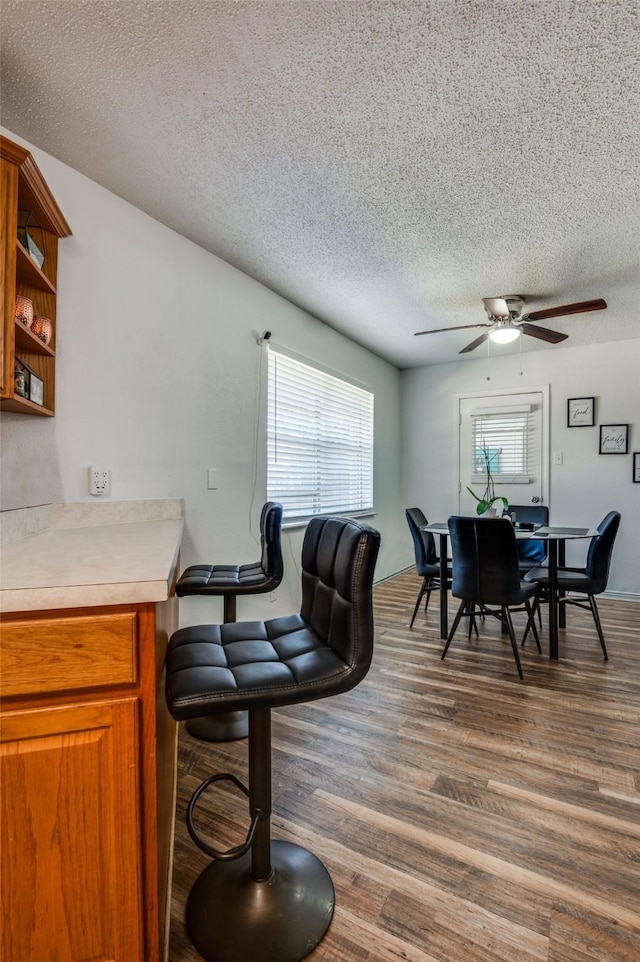 dining space with a textured ceiling, dark wood-style flooring, and a ceiling fan