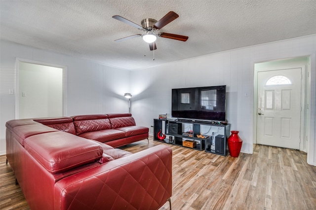 living area with ceiling fan, a textured ceiling, and wood finished floors