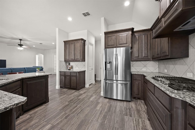 kitchen with light stone countertops, dark brown cabinetry, arched walkways, and stainless steel appliances