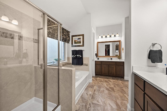 bathroom featuring a garden tub, vaulted ceiling, a shower stall, and vanity