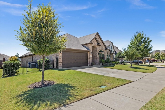 french country inspired facade featuring driveway, an attached garage, fence, a front lawn, and brick siding