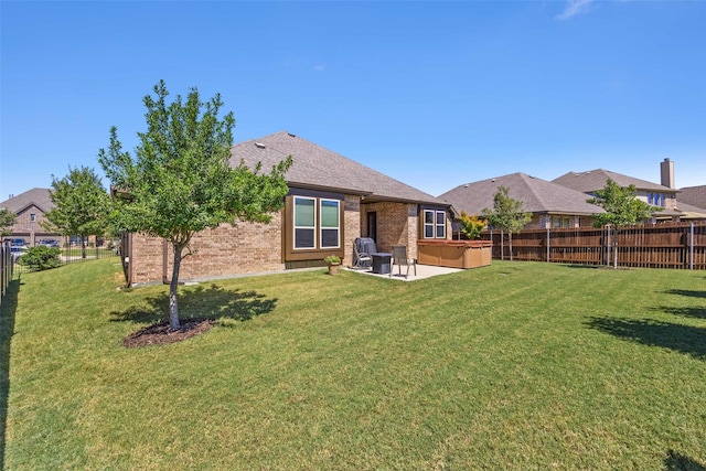 rear view of property with brick siding, a lawn, a hot tub, a patio area, and a fenced backyard