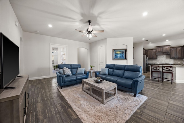 living area featuring arched walkways, recessed lighting, and baseboards